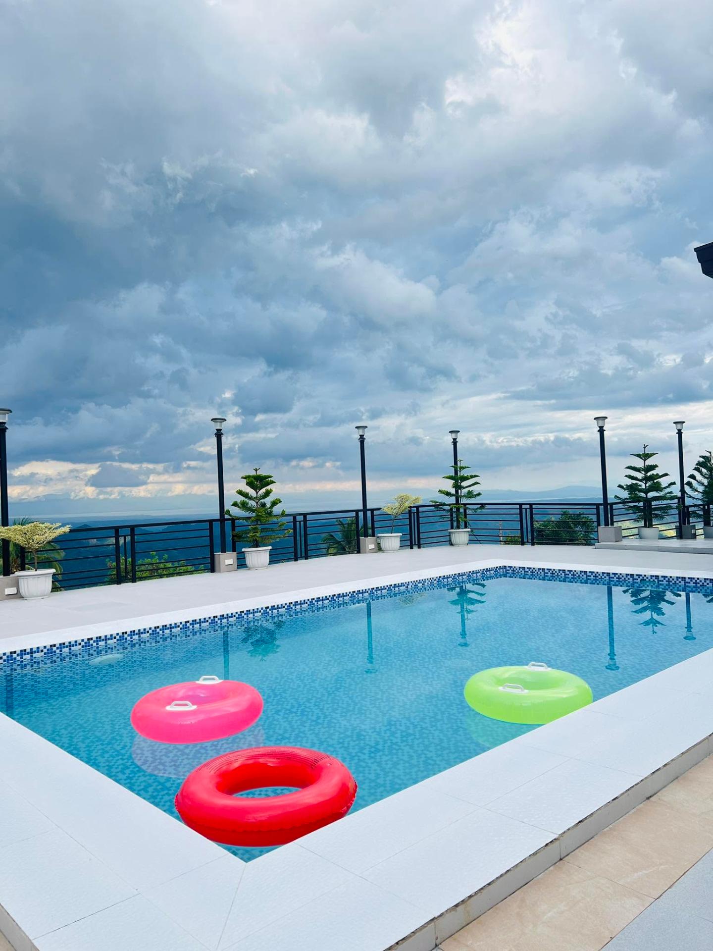 Pool with floaties, cloudy sky, mountains behind